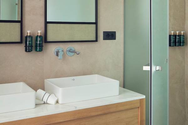 Badezimmer im Melia Durres Albania Hotel mit zwei Waschbecken, Spiegeln und Dusche.