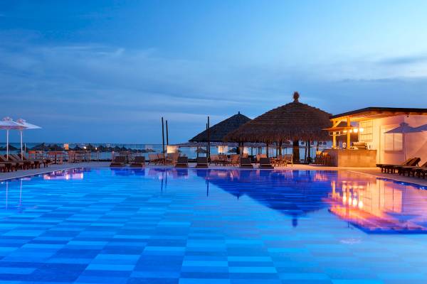 Abendlicher Blick auf den Pool des Melia Durres Albania Hotels mit Sonnenliegen und Bars.