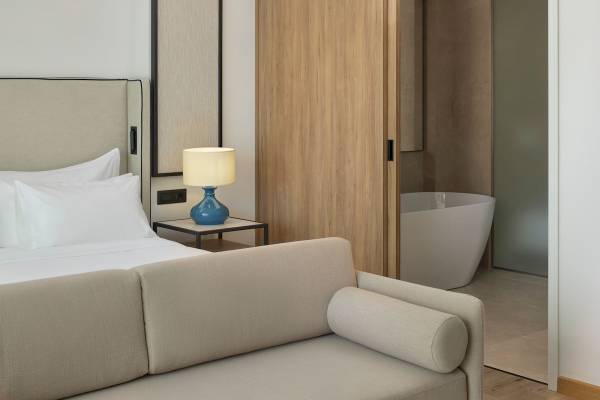 Schlafzimmer im Melia Durres Albania Hotel mit Sofa, Bett, Lampe und Badewanne.