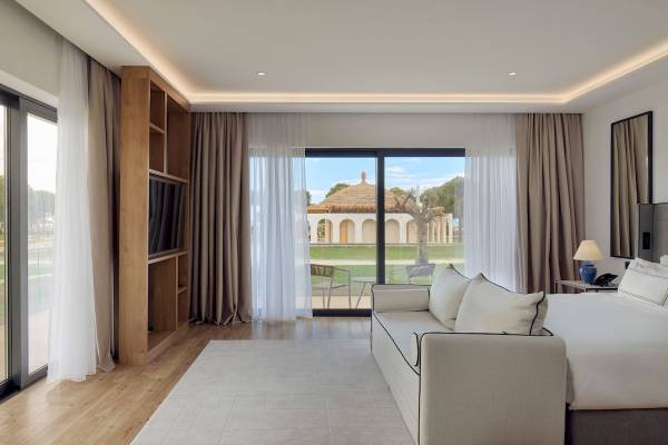 Innenansicht eines Hotelzimmers im Melia Durres Albania mit einem großen Bett, einem Fernseher und einer Aussicht auf eine Terrasse.