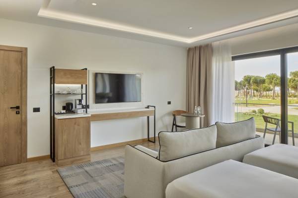 Innenansicht eines Zimmers im Melia Durres Albania Hotel mit Fernseher, Schreibtisch und Sofa.