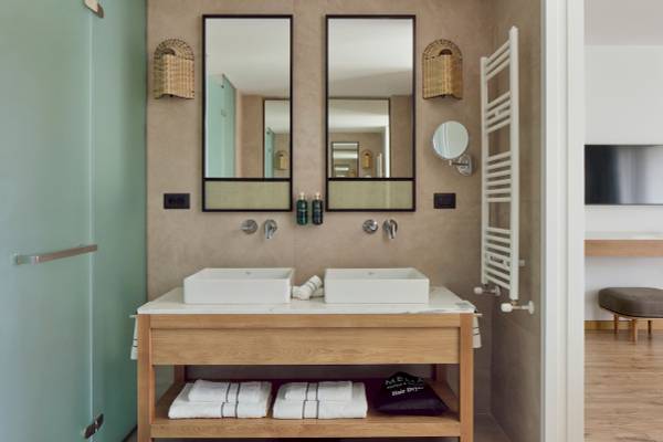 Badezimmer im Melia Durres Albania Hotel mit zwei Waschbecken, Spiegeln und Handtüchern.