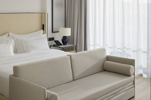 Schlafzimmer im Melia Durres Hotel in Albanien mit Bett, Sofa und Nachttisch.