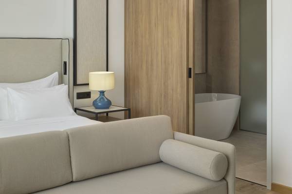 Innenansicht des Schlafzimmers im Melia Durres Albania Hotel mit Bett, Couch, Nachttisch und Badewanne.