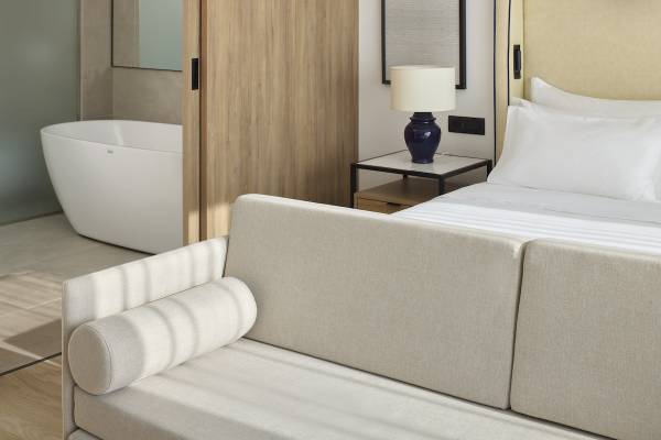 Hotelzimmer des Melia Durres Albania mit Sofa und Bett, neben Badewanne und Nachttisch.