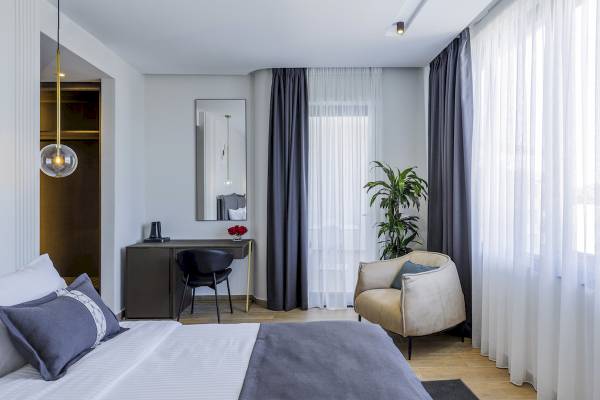 Innenansicht eines Schlafzimmers im Mövenpick Hotel Lalez Durres mit Bett, Schreibtisch und Möbeln.