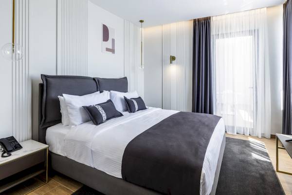 Schlafzimmer im Mövenpick Hotel Lalez Durres mit einem großen Bett, weißen Wänden und modernen Möbeln.