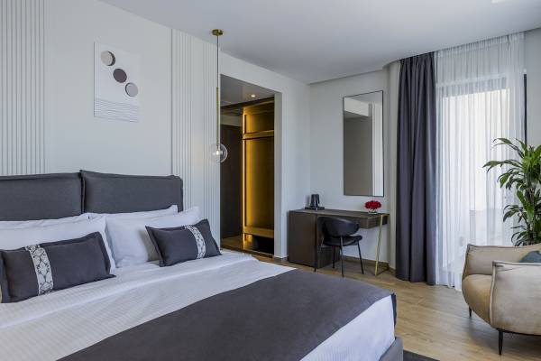 Schlafzimmer im Mövenpick Hotel Lalez Durres mit Bett, Nachttisch, Spiegel und moderner Einrichtung.