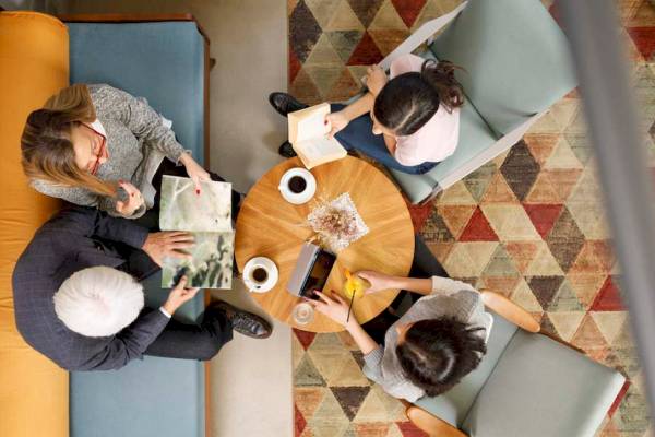 Vier Gäste des Mövenpick Hotel Lalez Durres sitzen in einem modernen Loungebereich und lesen Bücher.