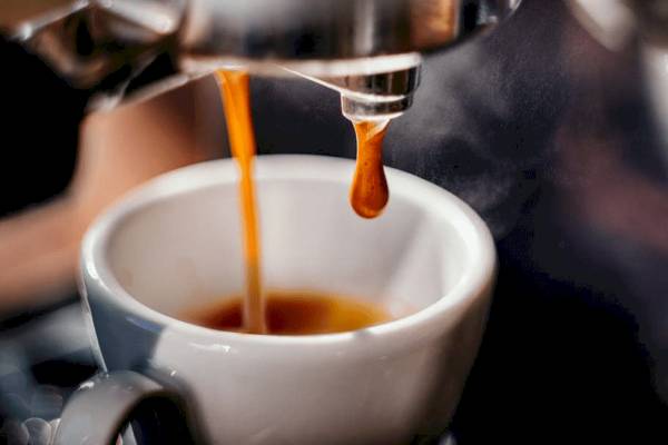 Kaffee wird in eine weiße Tasse gebrüht, die auf einem Untersetzer steht.