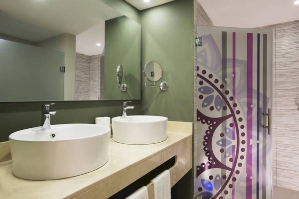 Badezimmer im Emotions By Hodelpa Hotel in Puerto Plata mit zwei Waschbecken und grün gestrichenen Wänden.