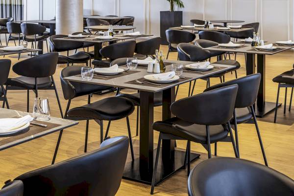 Innenansicht des Restaurants im Mövenpick Hotel Lalez Durres mit gedeckten Tischen und Stühlen.