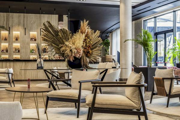 Loungebereich im Mövenpick Hotel Lalez Durres mit modernen Möbeln, Pflanzen und einer großen Blumenvase.