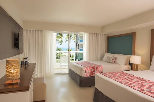 Hotelzimmer im Emotions By Hodelpa Puerto Plata mit Blick auf das Meer, zwei Betten und eine Terrasse.