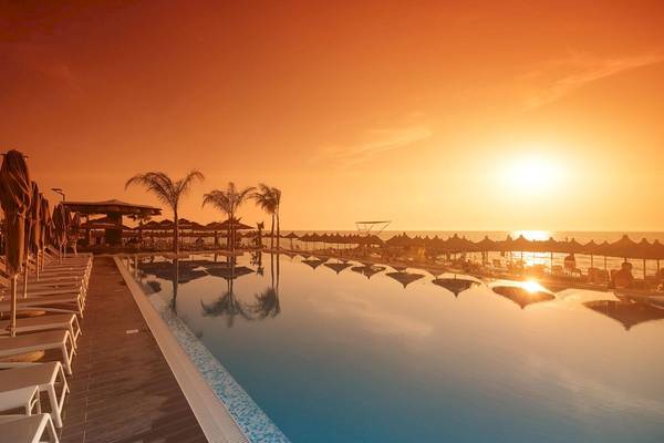 Der Sunset-Blick auf den Swimmingpool und die Sonnenschirme im Brilliant Hotel & Spa.