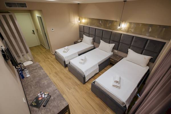 Dreibettzimmer im Brilliant Hotel & Spa mit drei Betten, Nachttischen und Fernseher.
