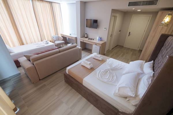 Doppelzimmer im Brilliant Hotel & Spa mit zwei Betten, einem Sofa und einem Fernseher.