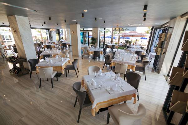Innenbereich des Brilliant Hotel & Spa mit mehreren gedeckten Tischen und Stühlen.