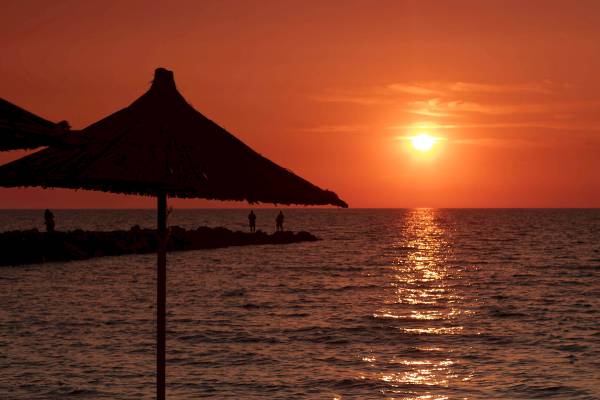 Sonnenuntergang am Strand mit Sonnenschirm und Liegen am Brilliant Hotel & Spa