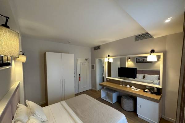 Ein modernes Hotelzimmer im Sandy Beach Resort mit einem großen Bett, einem Schreibtisch und einem Spiegel.