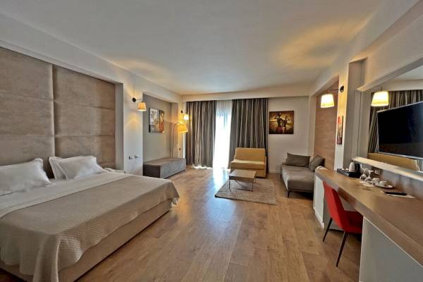 Schlafzimmer im Sandy Beach Resort mit einem großen Bett, zwei Nachttischen, einem Fernseher und einem Schreibtisch.