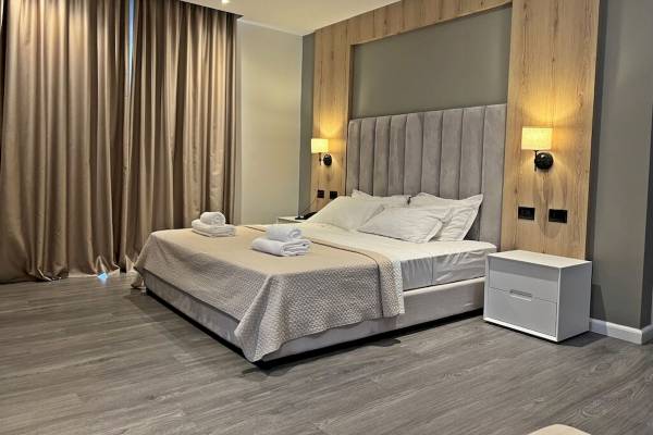 Ein elegantes Schlafzimmer im Sandy Beach Resort mit einem großen Bett, frischen weißen Kissen und zwei Nachttischen.