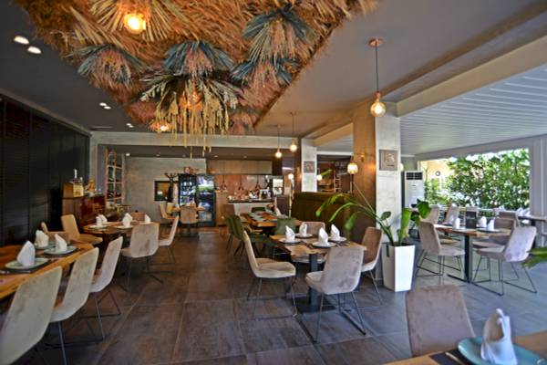 Restaurant-Innenansicht des Sandy Beach Resorts mit gedämpften Lichtern, Holztischen und Stühlen.