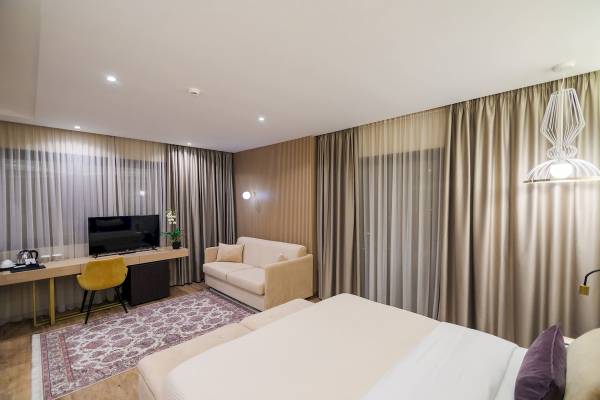 Interieur eines Zimmers im Gloria Palace Hotel mit Bett, Sofa, Schreibtisch und Fernseher.
