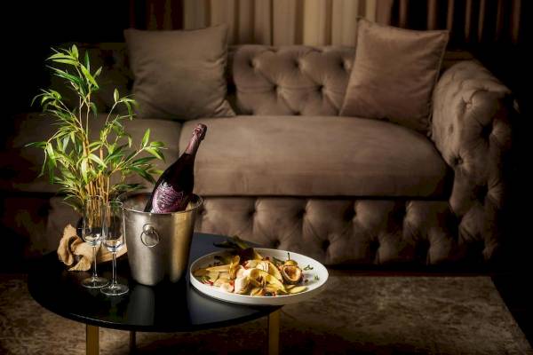 Ein Sofa mit einem Tisch davor, auf dem eine Flasche, Obst und Gläser stehen.
