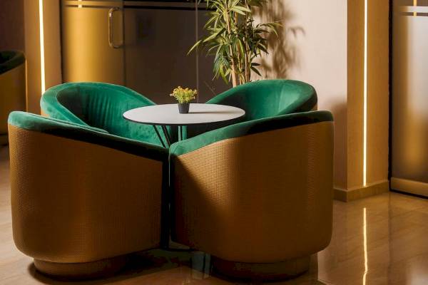 Hotel-Lounge mit grünen Sesseln und einem Tisch, auf dem eine kleine Pflanze steht.