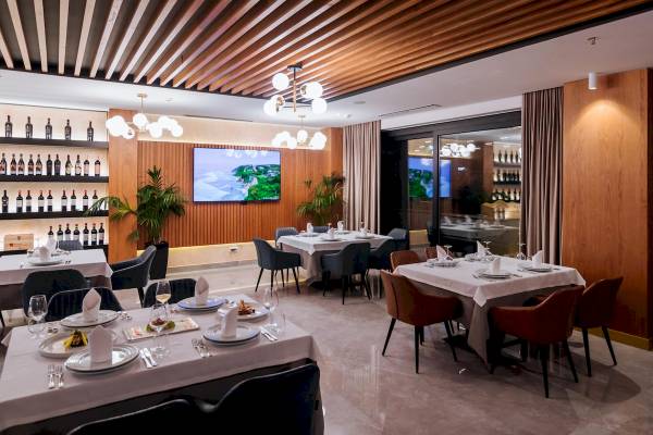 Innenansicht des Restaurants im Gloria Palace Hotel & SPA mit gedeckten Tischen und dekorierten Pflanzen.