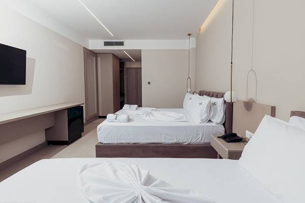 Innenansicht eines Doppelzimmers im Delight Hotel mit zwei Betten, Fernseher, Schreibtisch und modernen Möbeln.