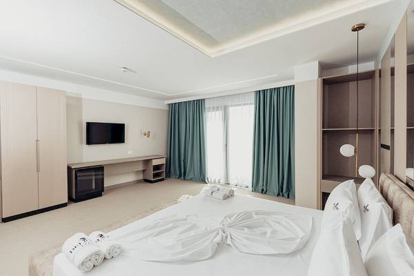 Innenansicht eines Zimmers im Delight Hotel mit einem großen Bett, einem Fernseher an der Wand und einem Schreibtisch.