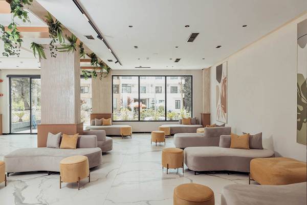 Lobbybereich des Delight Hotels mit bequemen Sofas und Hockern in einer modernen Einrichtung.