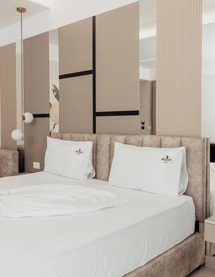 Schlafzimmer im Delight Hotel mit zwei weißen Kissen und einem gerahmten Spiegel.