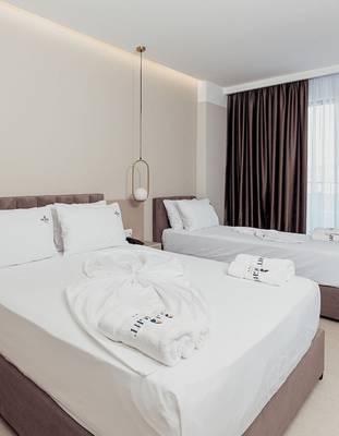 Doppelzimmer im Delight Hotel mit zwei Betten, weißen Laken, Kissen und Handtüchern.