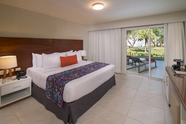 Hotelzimmer im Emotions By Hodelpa Puerto Plata mit Doppelbett, Poolblick und Glastür.