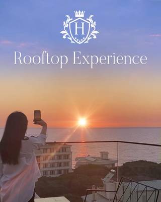 Eine Frau fotografiert den Sonnenuntergang vom Dach des Henry Resort & Spa aus.