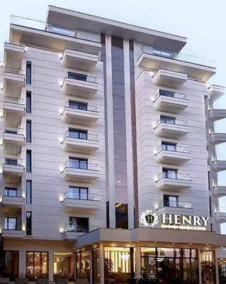 Außenansicht des Henry Resort & Spa mit vielen Balkonen und leuchtenden Fenstern.