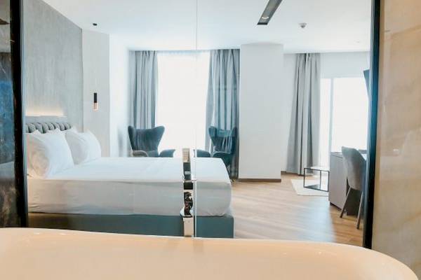 Schlafzimmer im Klajdi Resort & SPA Hotel mit Doppelbett, Badewanne und Meerblick.