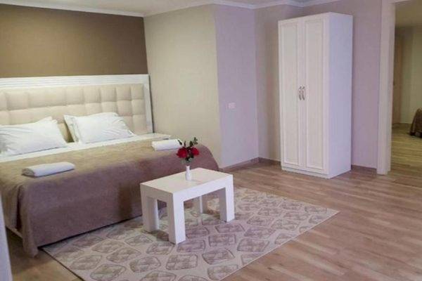 Schlafzimmer im Klajdi Resort & SPA mit Bett, Tisch, Blumen und Schrank.