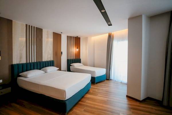 Zwei Betten im Schlafzimmer des Klajdi Resort & SPA, beide mit weißen Laken und Kissen, neben einem Nachttisch.