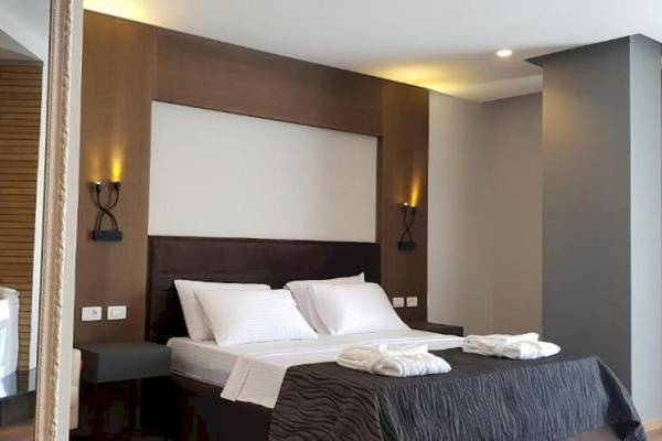 Schlafzimmer im Klajdi Resort & SPA mit einem großen Bett, weißen Kissen und einem Badewanne.