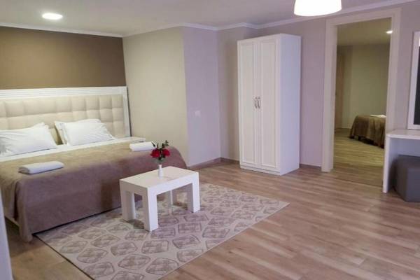 Schlafzimmer im Klajdi Resort & SPA mit einem Bett, Tisch, Vase mit Blumen und Schrank.