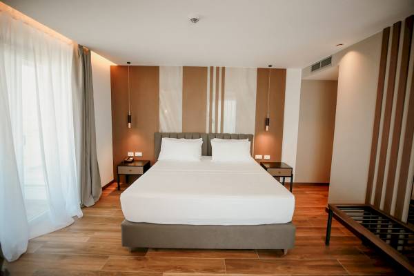 Schlafzimmer im Klajdi Resort & SPA mit einem Doppelbett, zwei Nachttischen und einer modernen Einrichtung.
