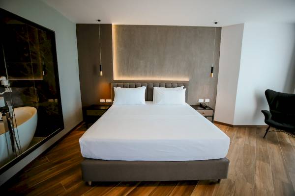 Ein Bett im Klajdi Resort & SPA mit weißen Laken und Kissen auf einem hölzernen Boden.
