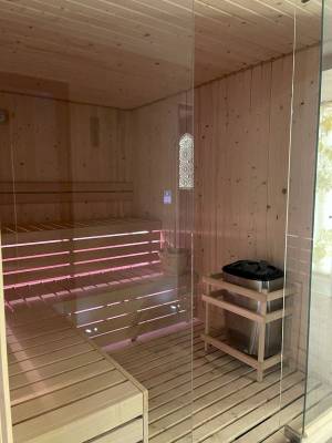 Innenansicht der Sauna im Klajdi Resort mit Holzwänden und Bänken, die mit roten Lichtern beleuchtet sind.