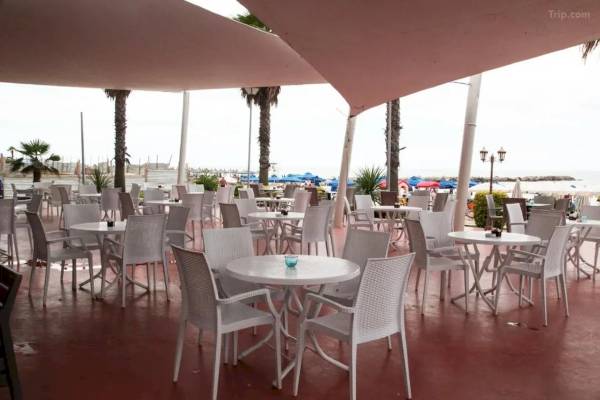Außenterrasse des Fafa Beach Hotel mit vielen weißen Tischen und Stühlen, teilweise überdacht.