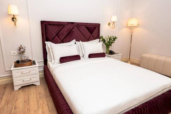 Schlafzimmer im Diamma Resort mit einem großen Bett, weißen Laken, roten Kopfkissen und Möbeln.