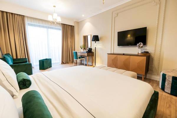 Schlafzimmer im Diamma Resort mit einem großen Bett, grünen Kissen und einem Fernseher an der Wand.